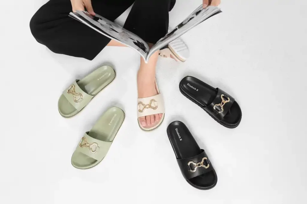 Sepatu sandal slip-on Elizabeth dengan aksen rantai elegan, ditampilkan dalam berbagai warna dan ukuran, cocok untuk gaya kasual wanita.